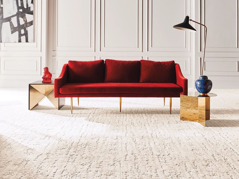 Bright living room with red velvet couch and beige textured carpet from The Carpet Shoppe Inc in Tulare, CA